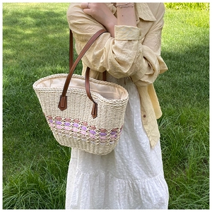 Detail of hand-woven straw tote with purple diamond pattern and brown leather straps