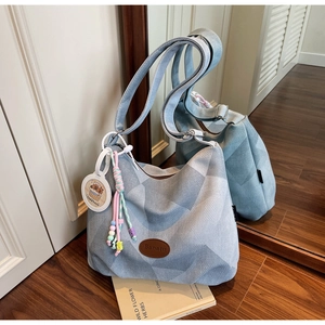 Detalle del bolso tote de lona azul geométrica con logo de cuero y colgante Capybara