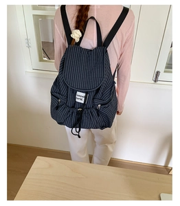 Detail eines karierten Rucksacks mit Kordelzug, Markenlogo und Reißverschlusstasche