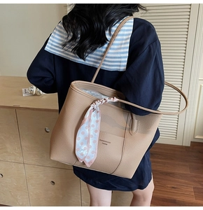 Detailed macro view of beige lychee texture leather tote bag with silk scarf detail