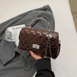 Detailed view of dark brown quilted leather handbag with silver chain and metal ball charm