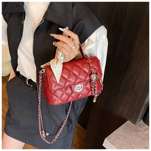 Detail of red quilted crossbody bag with silver twist lock and decorative silk scarf