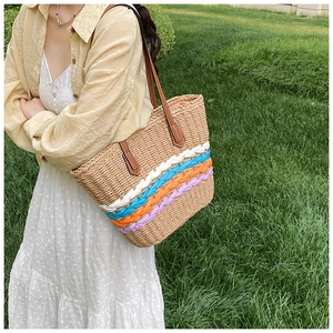 Detail of colorful woven stripes on a straw tote bag with brown leather straps