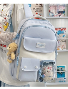 Detail of light blue canvas backpack with plush bear charm and clear cat doll pocket