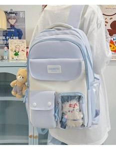 Detail shot of blue and beige school backpack with transparent pocket and plush charms