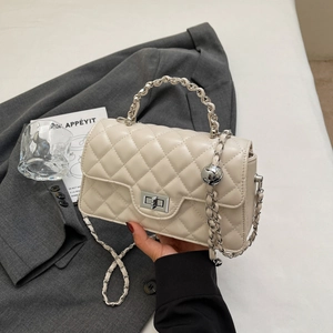 Detailed macro view of cream quilted shoulder bag with silver chain strap and metal clasp