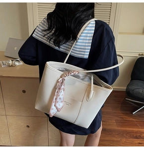 Detail of elegant beige textured leather tote bag with a pink polka dot scarf on the handle