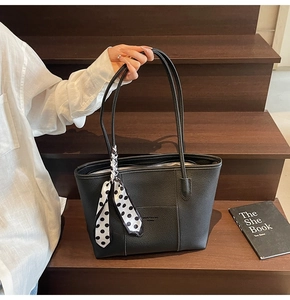 Detail of black pebbled leather tote bag with polka dot scarf and contrast stitching