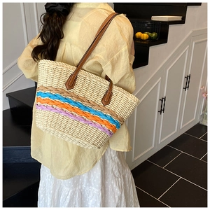 Detail of hand-woven straw tote bag with colorful stripes shown on model for resort style