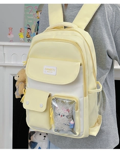 Detail view of cream and white school backpack with a transparent window pocket and cute bear charm