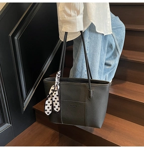 Close-up of black lychee leather tote bag with stylish polka dot scarf on stairs