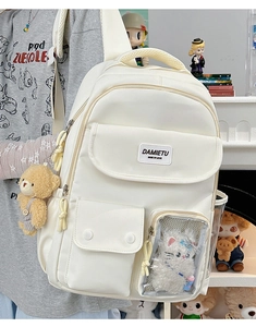 Close-up of a white functional backpack featuring cute plush charms and multiple pockets