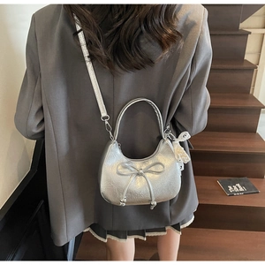 Détail du sac croissant argenté avec tissu froissé métallisé et nœud décoratif