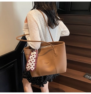 Detail of a brown lychee pattern tote bag featuring a polka dot scarf on the handle