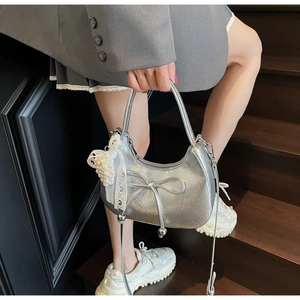 Détail du sac croissant argenté avec nœud décoratif et pendentif en perles et dentelle