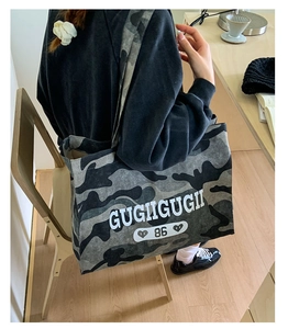 Detail of canvas tote bag featuring gray camouflage pattern and GUGIIGUGII logo