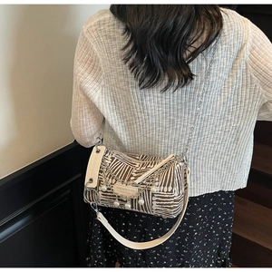 Detail view of striped tote bag with pearl chain and double straps on a model back