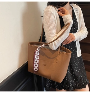 Detail of brown lychee grain leather tote bag with silk scarf and logo on long straps
