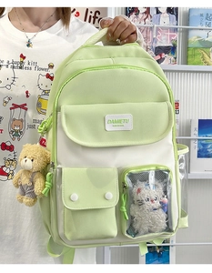 Detail of light green canvas backpack with transparent window and plush bear charm