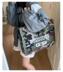 Close-up of camouflage waterproof tote bag with large white letter print and durable strap