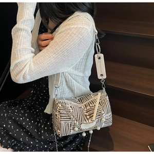 Detail of striped tote bag with silver chain and pearl pendant shown on model