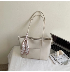 Detail of minimalist cream leather tote bag with polka dot scarf and front pocket