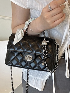 Quilted black crossbody bag with silver skull charm and silk scarf handle detail