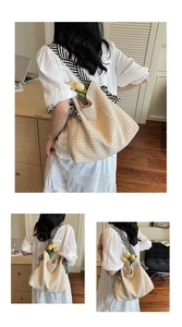 Detail of beige woven straw tote bag with striped strap and tulip decoration for summer beach