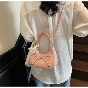 Vue détaillée du sac hobo croissant rose avec nœud et pendentif perle dentelle