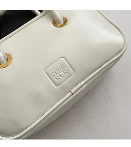 Detail of cream leather handbag featuring gold eyelets and CLEA R♡K embossed logo