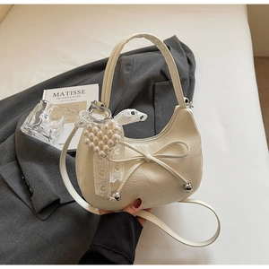 Détail du sac hobo en croissant avec nœud en cuir et breloque de cœur en perles