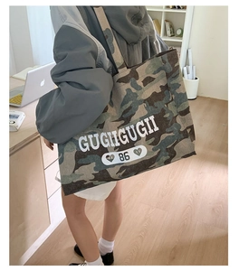 Close-up of durable camo tote bag with large white logo print and sturdy canvas texture