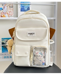 Detailed view of cream backpack with transparent pocket, cat plush, and bear charm