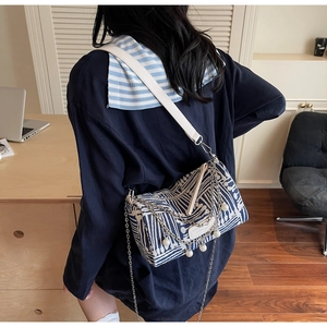 Detail of blue and white striped tote bag with pearl chain charms in office setting
