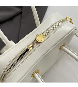 Close-up of smooth gold zipper and KCLEAR logo on a premium white leather handbag