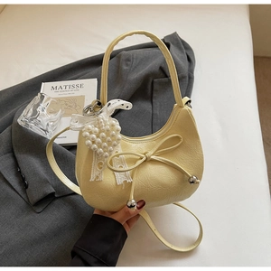 Détail du sac croissant jaune clair avec nœud en dentelle et pendentif cœur perlé