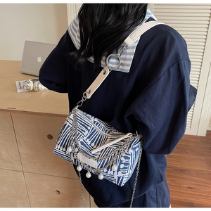 Detail view of blue and white printed cylinder bag with silver chains and pearls