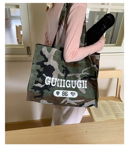 Detail shot of camouflaged canvas tote bag with GUGIIGUGII logo and durable long shoulder strap