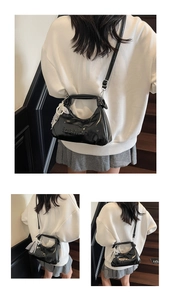 Detail of black glossy handbag featuring fashion embossing and a pearl lace pendant