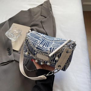 Detail of blue and white striped barrel tote bag featuring pearl chain and leather strap