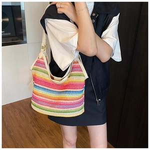Detail of colorful rainbow woven straw tote bag with white leather straps and gold buckles