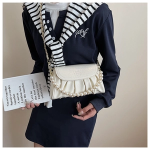 Détail d'un sac nuage plissé blanc crème avec chaîne de perles et lettres gravées décoratives