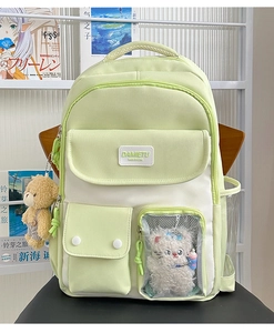 Detail view of light green school backpack with transparent mesh pocket and plush pendants