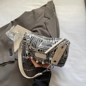 Detail of striped cylinder tote bag with silver chains, pearls and white leather strap