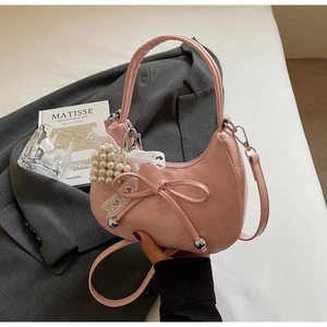 Détail du sac demi-lune rose avec nœud délicat, dentelle blanche et perles