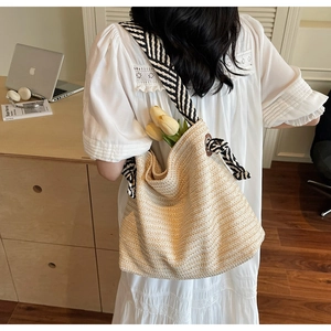 Close-up of woven straw tote bag with black and white geometric wide shoulder strap