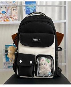 Detail view of black and white backpack with transparent PVC window and cat plush accessory