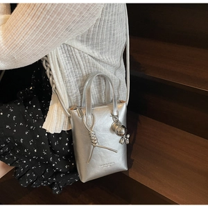 Dettaglio di una borsa porta cellulare argento metallizzato con nodo e ciondolo