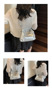 Detail of silver metallic fashion bag with lace bow charm and embossed lettering