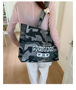 Detail view of oversized camouflage tote bag with white letter print and heart graphic